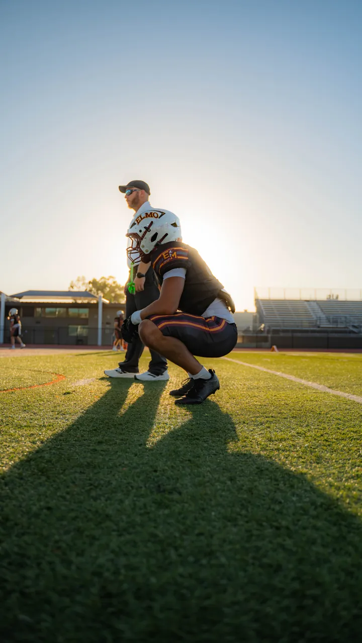 Player kneeling in golden backlight before a game, El Modena vs. Foothill
