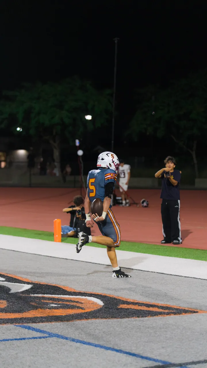 Runner sprinting down the sideline under the lights