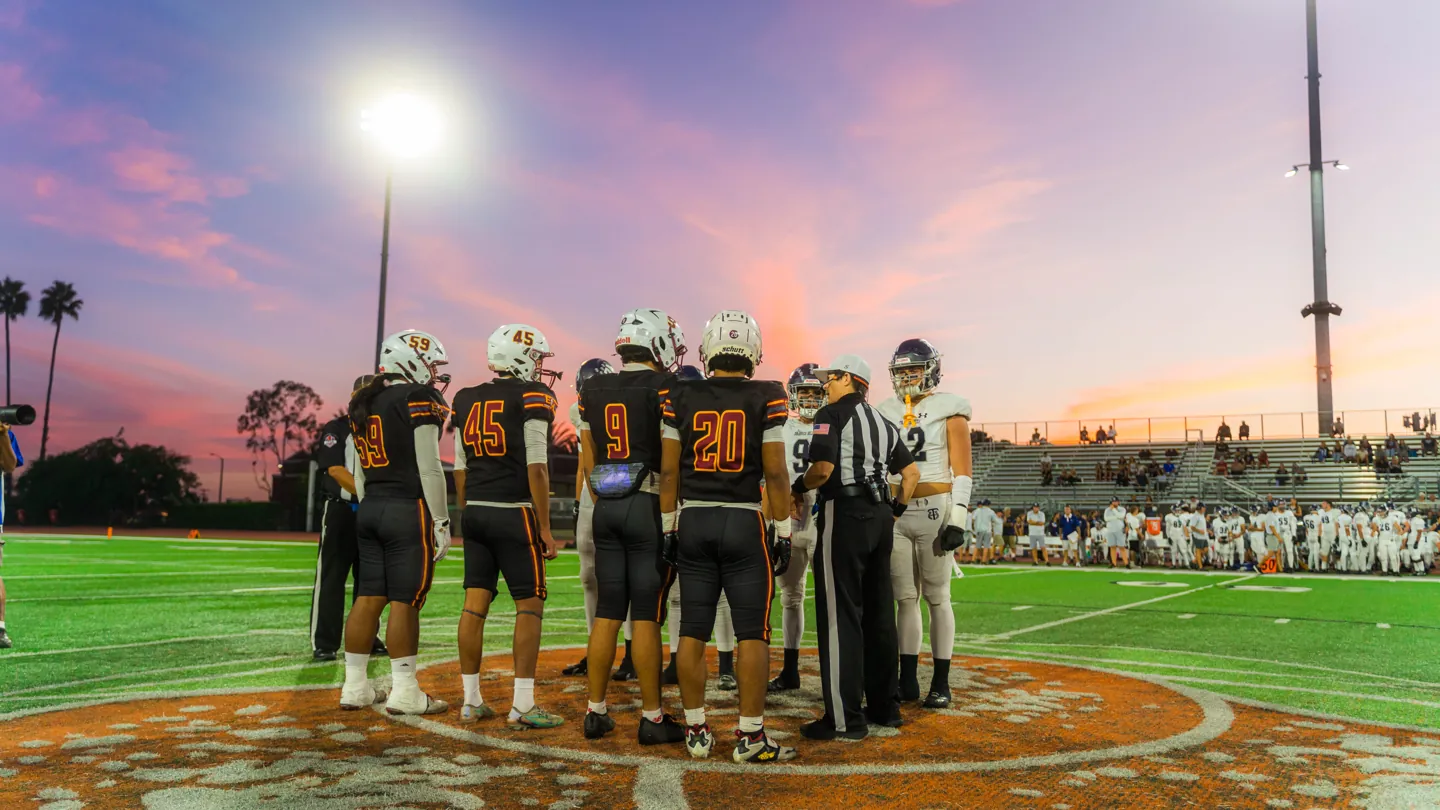 Captains meet at midfield for the coin toss under a pink sunset, El Modena vs. Trabuco