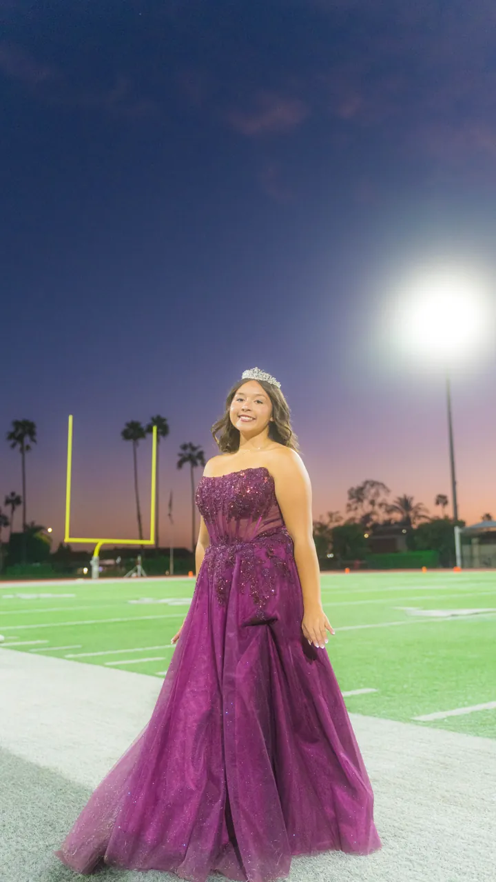 Homecoming court on the field at dusk under the stadium lights